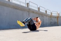 Junger Mann macht mittags Sit-ups ohne Hemd auf der Straße — Stockfoto