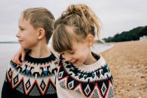 Siblings hugging and laughing together on the beach in the UK — Stock Photo