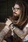 Hipster guy with dreadlocks and tattoo sitting on the beach in thailan — Stock Photo