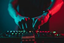Close up of Dj hands mixing and adjusting volume in a synthesizer — Stock Photo