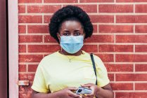 Portrait of African American Girl with face mask on red brick wall background. — Stock Photo