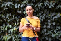 Giovane donna che ascolta la musica attraverso il suo smarthphone per strada — Foto stock
