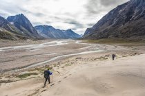Two backpackers hiking through mountainous valley, Baffin Island — Stock Photo