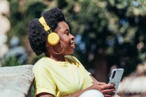 Afro americana menina ouvindo música com seu telefone celular e fones de ouvido. — Fotografia de Stock