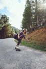 Uma mulher com um skate em uma estrada de montanha — Fotografia de Stock