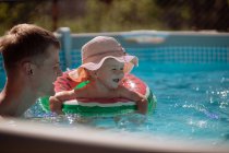 Bambina in cappello nuota in piscina con papà — Foto stock