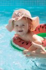Little girl in a hat swims in the pool — Stock Photo