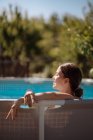 Young girl in backlight in the garden pool — Stock Photo