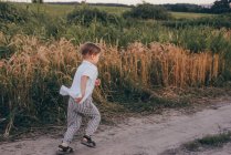 Portrait d'un petit garçon mignon heureux de 5 ans, portant une chemise blanche debout dans le champ sur l'herbe verte — Photo de stock