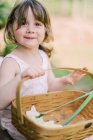 Kleines Mädchen mit einem Korb voller Blumen — Stockfoto