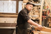 Молодой профессиональный плотник, работающий в мастерской — стоковое фото