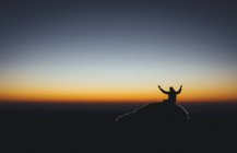 Silueta del hombre sobre el coche al amanecer - foto de stock