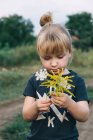 Carino bambina tenendo fiori di campo tra le mani — Foto stock