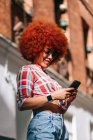 Mulher latina com cabelo afro usando telefone celular — Fotografia de Stock