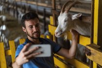 Ragazzo prende un selfie al telefono con una capra — Foto stock