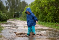 Happy child is jumping in a puddle. — Stock Photo
