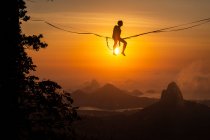 Beautiful view to male highliner silhouette over the sun on mountain landscape, Rio de Janeiro, Brazil - foto de stock
