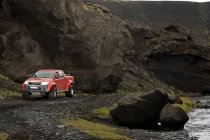 Красный автомобиль едет по дороге на фоне природы — стоковое фото