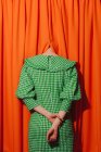 Девушка в зеленом платье, прячущая голову в оранжевых занавесках — стоковое фото