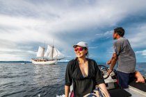 Woman approaching sail boat on dingy in Raja Ampat — Stock Photo