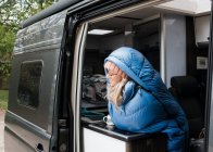 Женщина сидела, наслаждаясь чашкой кофе в спальном мешке в своем фургоне — стоковое фото