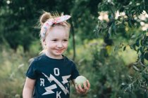 Cute girl holds a green apple in her hands — Stock Photo