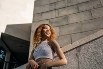 Stock photo of portrait of young blonde curly girl against the wall. She has confident attitude and looking at camera. She is wearing casual clothes - foto de stock