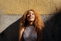 Stock photo of portrait of young blonde curly girl against the wall. She has confident attitude and looking at camera. She is wearing casual clothes - foto de stock