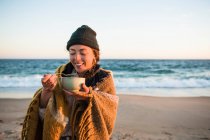 Jeune femme dégustant bol de soupe tandis que la voiture de plage camping à l'automne — Photo de stock