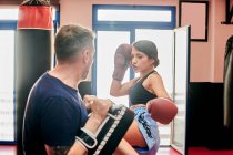 Young woman training with her Muay Thai trainer in a gym — Stock Photo