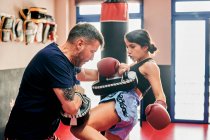 Young woman training with her Muay Thai trainer in a gym — Stock Photo