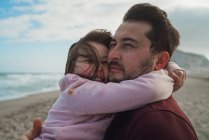 Батько тримає дочку на березі океану — стокове фото