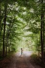 Netter Junge mit großem Wanderstock steht auf einem Pfad im Wald. — Stockfoto