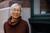 Lächelnde Seniorin mit Brille steht in der Stadt — Stockfoto