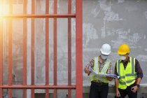 Ingenieur hält Bauplan in der Hand und diskutiert Projekt mit Baufirma — Stockfoto