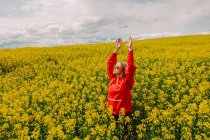 Blonde in sunglasses and red tracksuit in rapeseed field — Stock Photo