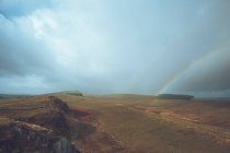 Uma paisagem interminável está cheia de arco-íris brilhantes no céu, enquanto na Muralha de Adriano, no Reino Unido. — Fotografia de Stock