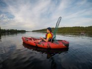 Teenage boy fishing in a kayak on a lake on a summer day. — Stock Photo