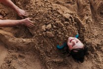 Pai enterra filha na areia na praia de Waikiki durante o pôr do sol — Fotografia de Stock