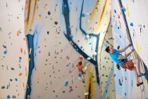 Uomo arrampicata sulla parete di arrampicata indoor a Londra — Foto stock