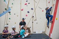 Тренер скелелазіння допомагає групі дівчат в приміщенні скелелазіння стіни — стокове фото