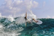 Людина з дошкою для серфінгу на морській хвилі на тлі чистого неба — стокове фото