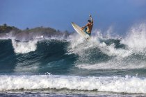 Mann mit Surfbrett surft auf Meereswelle gegen klaren Himmel — Stockfoto