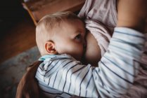 Close up of baby boy breastfeeding in cosy light — Stock Photo