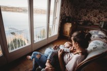 Mutter stillt Baby auf Stuhl in Vintage-Zimmer mit Blick auf den See — Stockfoto