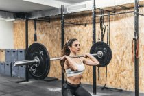 Femme avec haltères dans la salle de gym faire crossfit — Photo de stock