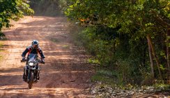 Hombre montando su moto de aventura en carretera polvorienta en Camboya - foto de stock