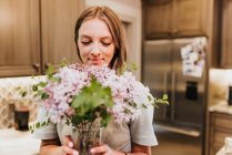 Bella giovane donna con mazzo di fiori a casa — Foto stock