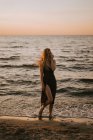 Молода жінка стоїть, посміхаючись біля моря . — стокове фото