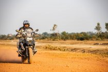 Homem montando sua moto de aventura na estrada de terra no Camboja — Fotografia de Stock